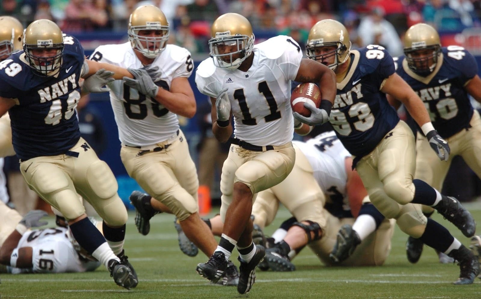 American football players in motion during a game, with one player carrying the ball while teammates block opponents.